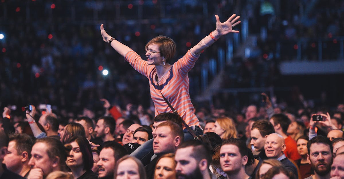 A woman joyfully cheers amidst a lively concert crowd, exuding energy.