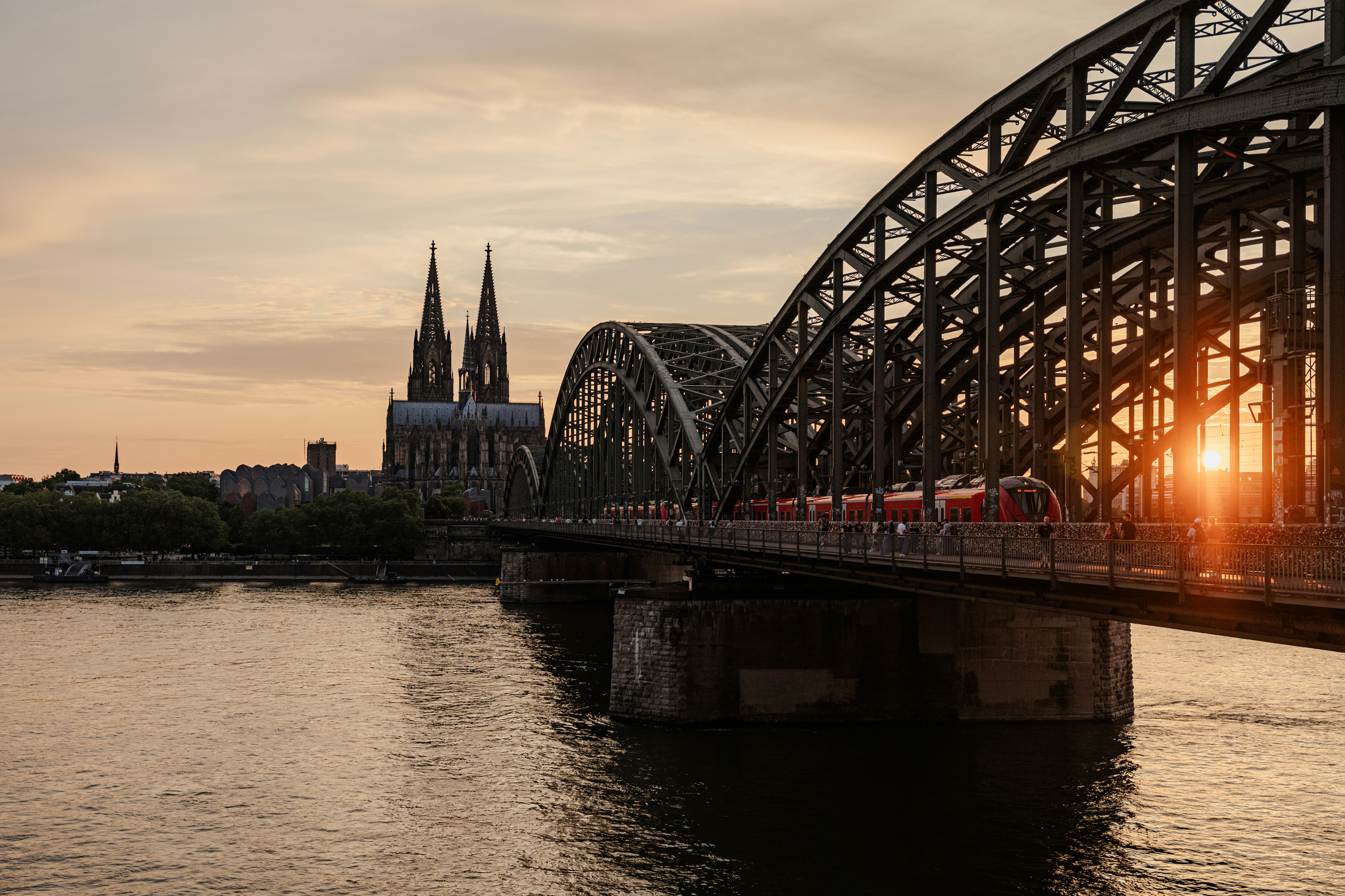 Train crossing a bridge with cathedral in background at sunset