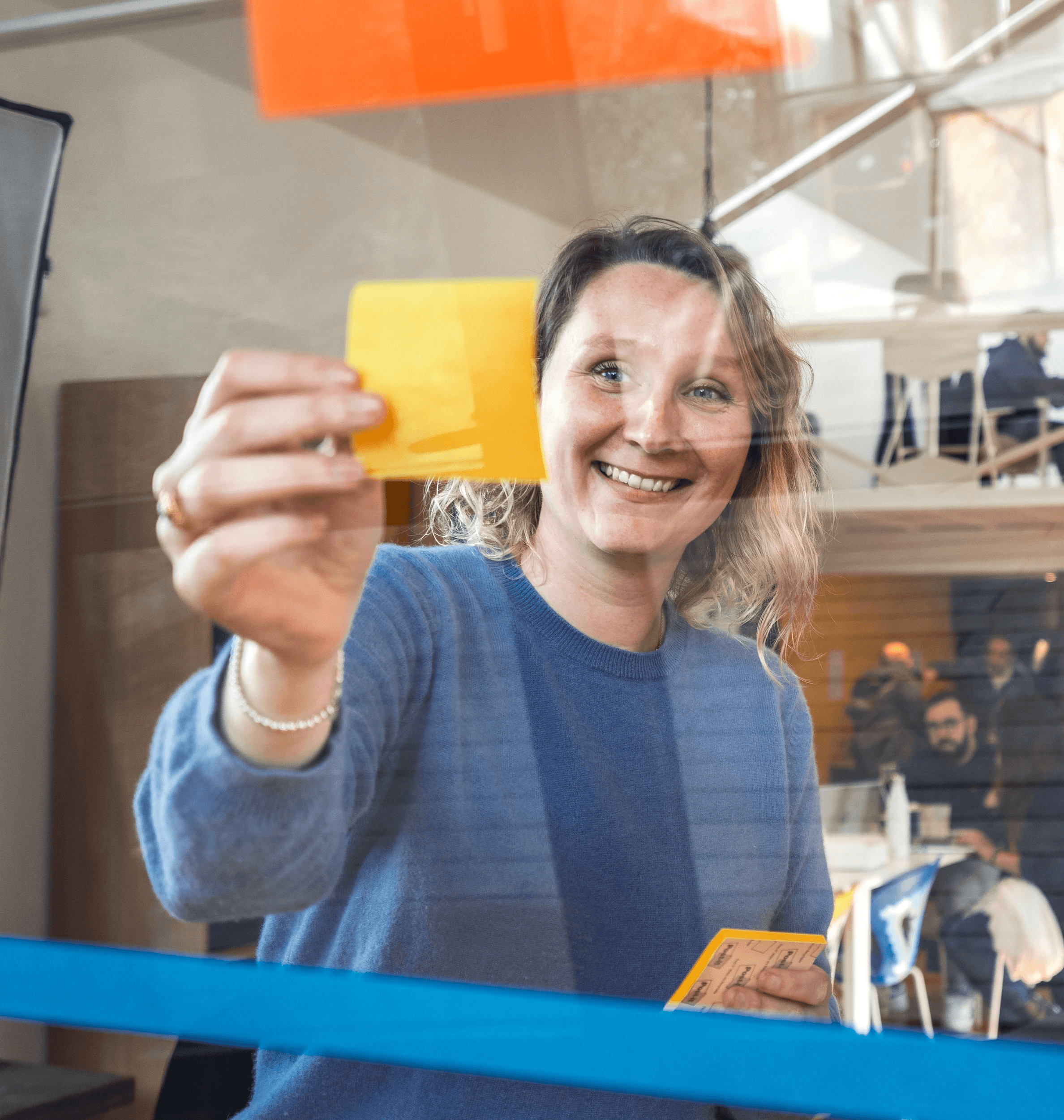 femme qui collent un post it sur une paroi transparente