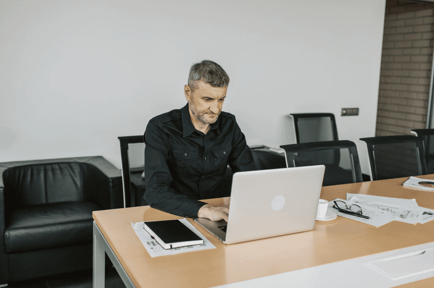 Man working on a laptop in a quiet meeting room, symbolising Amazon advertisers relying on isolated campaign setups that later cause cross-channel conflicts.