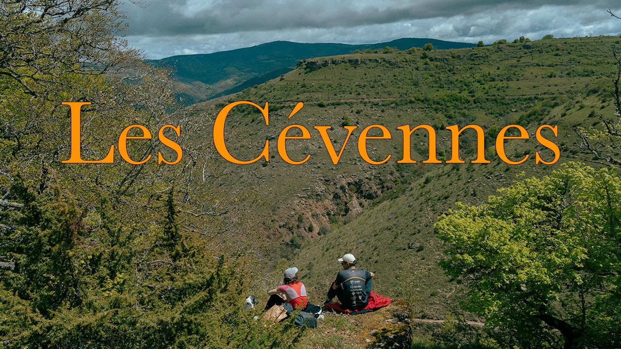 Deux randonneurs profitent d'une vue panoramique sur les montagnes verdoyantes des Cévennes.