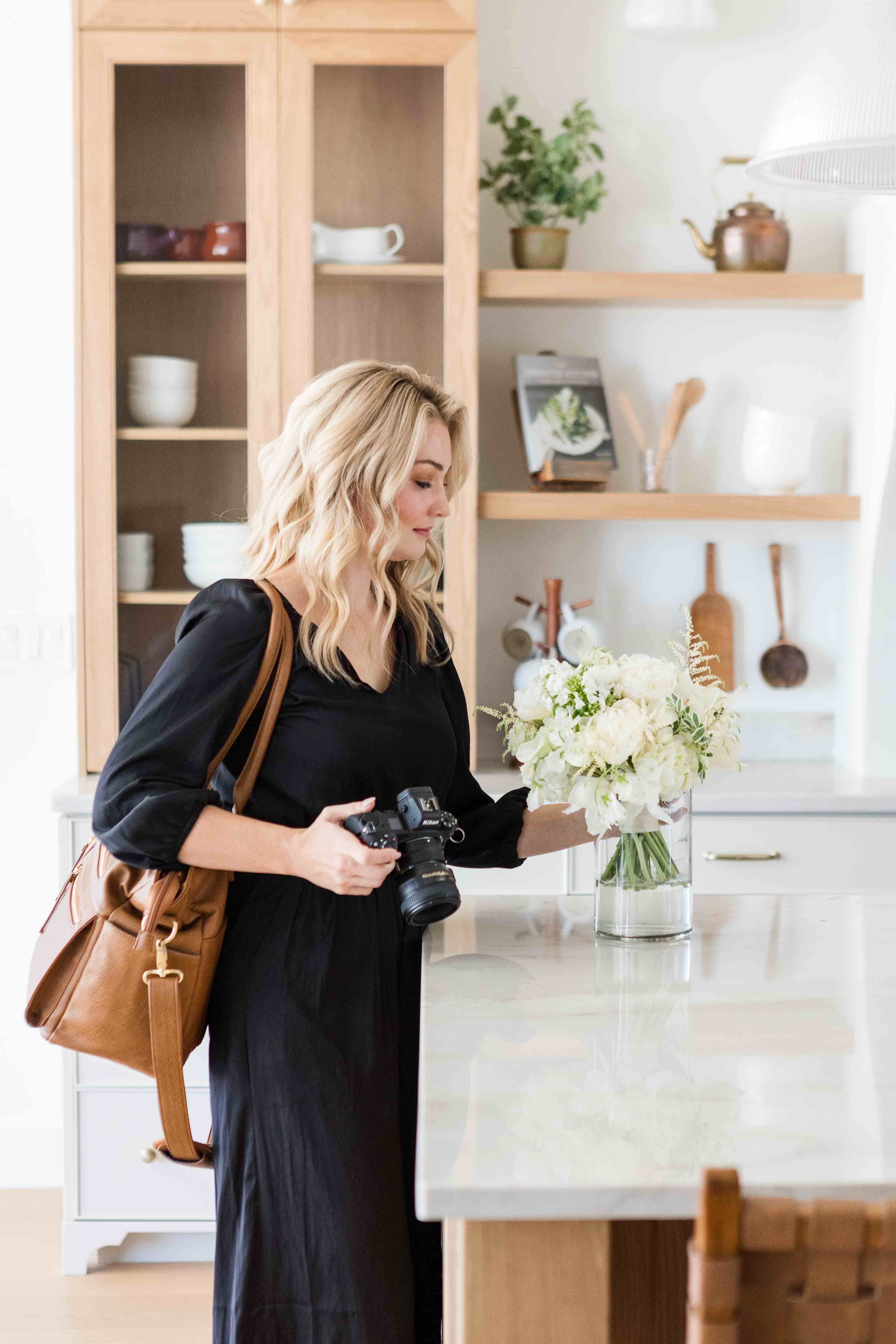 Headshot of wedding photographer holding camera and arranging florals in Nashville, Tennessee.