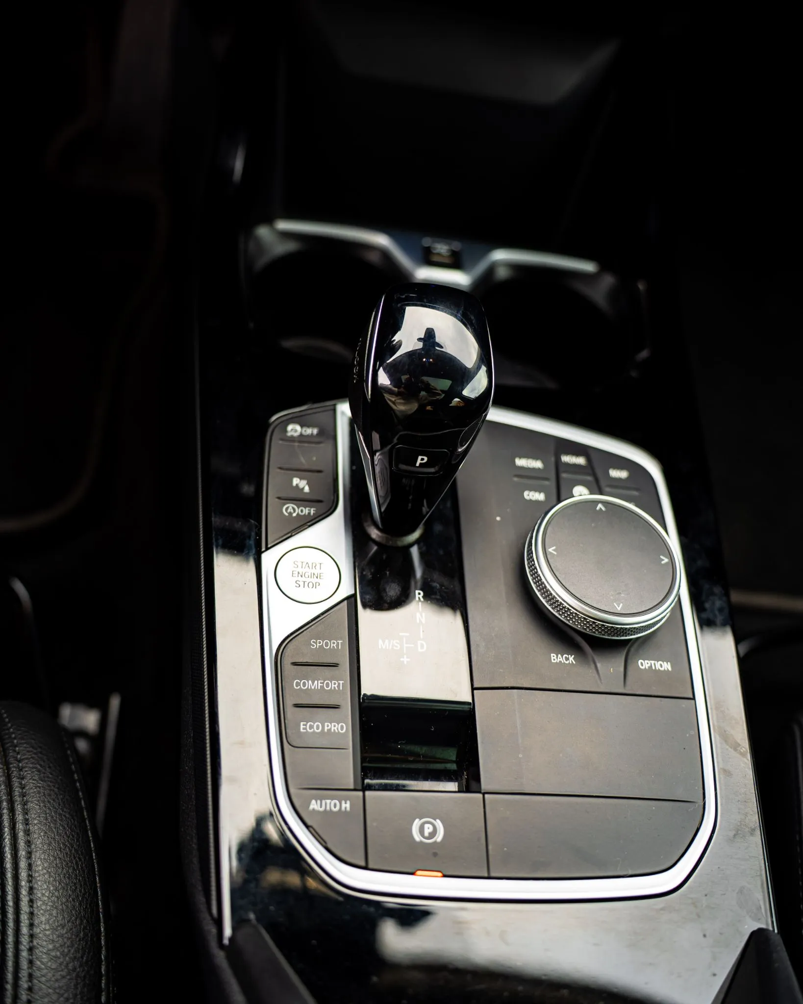 Consola central del BMW 220d con selector de cambios, botón start/stop y perilla multimedia