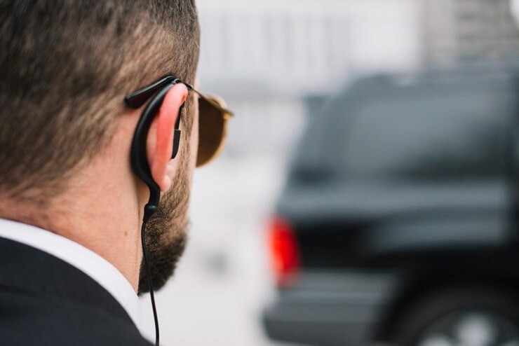 Agent de sécurité privée de dos avec des lunettes de soleil qui se dirige vers un véhicule type 4x4
