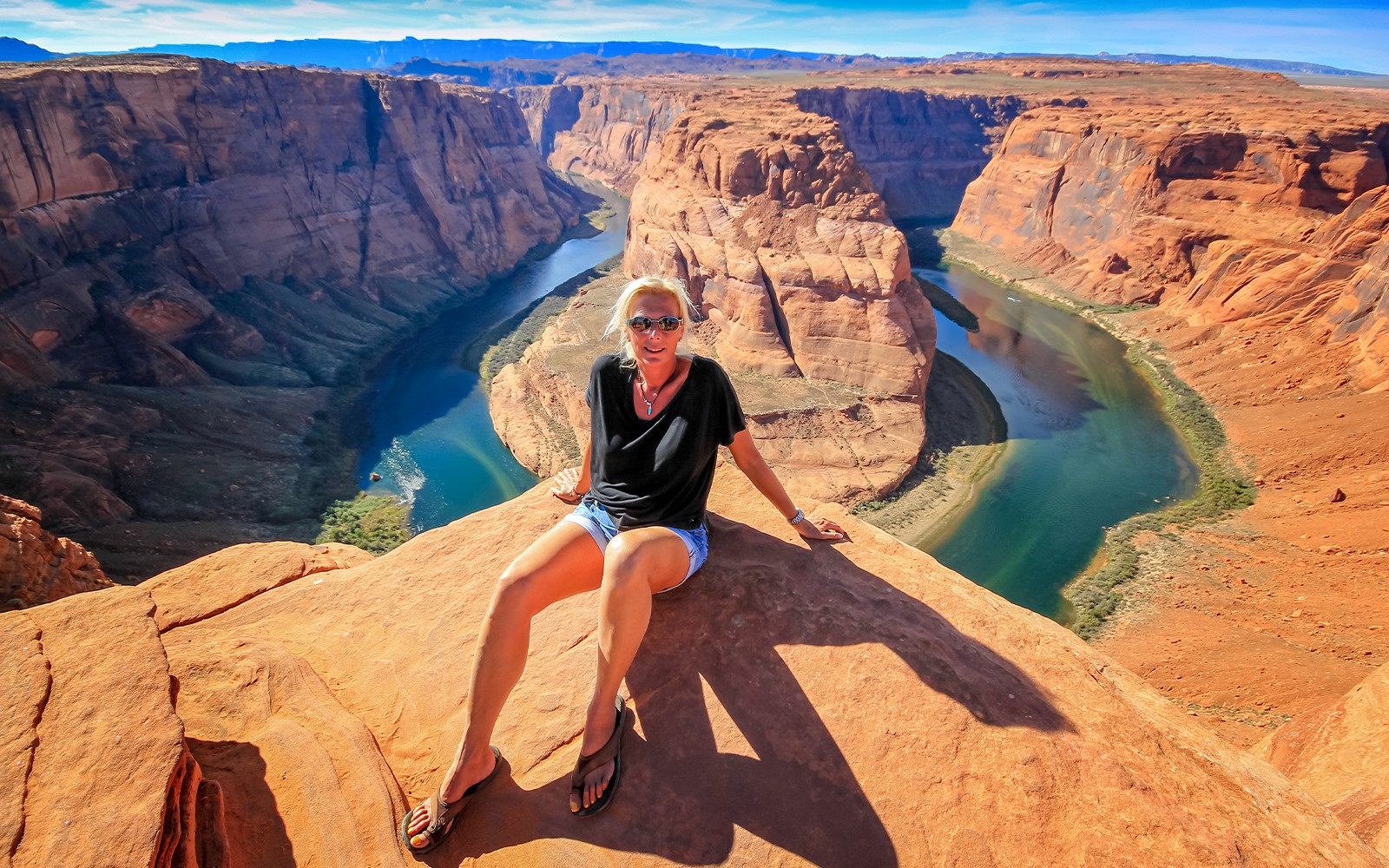Horseshoe Bend view with person sitting on rock, part of Secret Antelope Canyon tour.