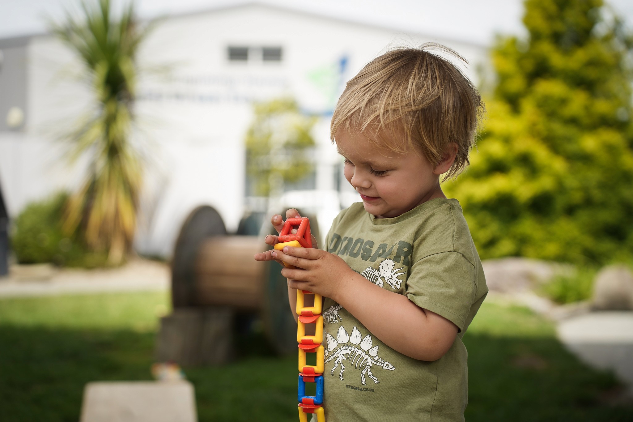 A young boy outside playing with a red ball
