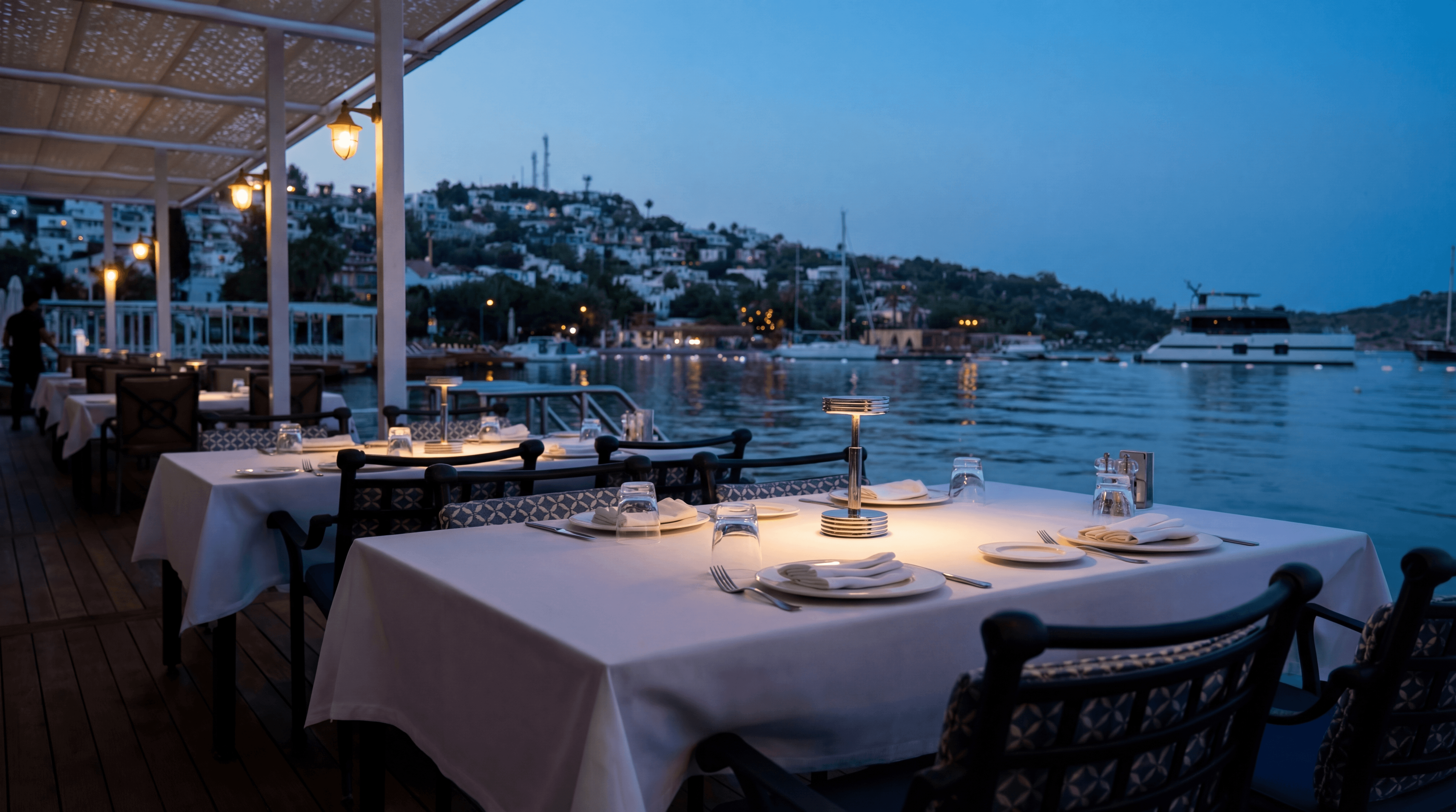 Seafront dinner table at Divan Türkbükü in Bodrum at sunset with waterfront views and candlelit setting