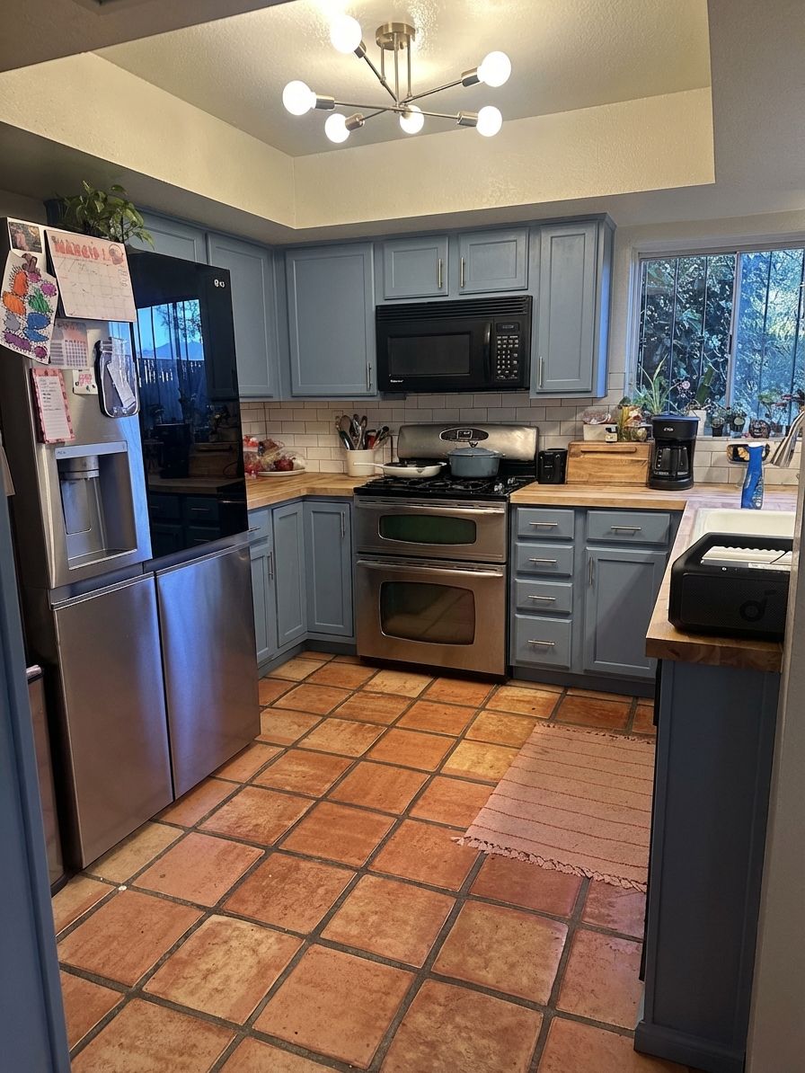 Dusty blue cabinets with white subway tile and brushed nickel on Saltillo floors