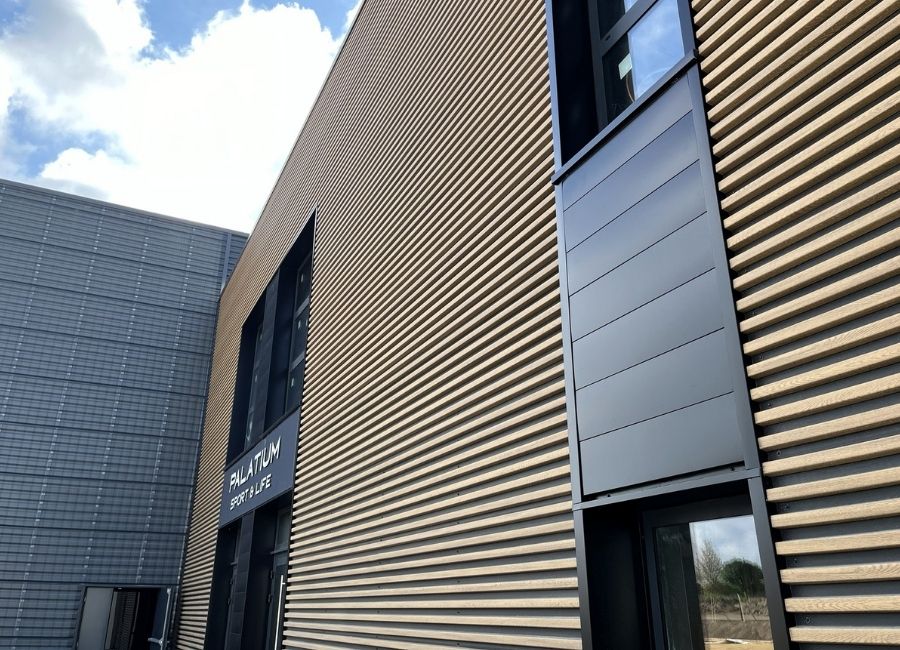 Bardage métallique ondulé noir et beige sur façade de bâtiment moderne, en finition.