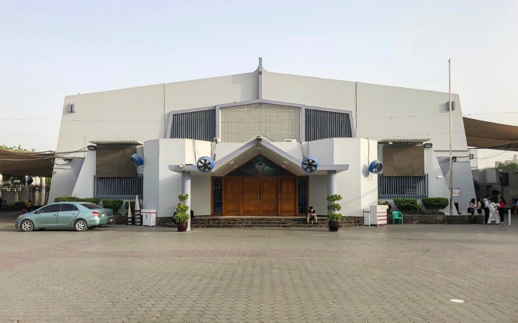 Modern facility near Business Bay with fans, columns, potted plants, and people gathered outside the entrance.