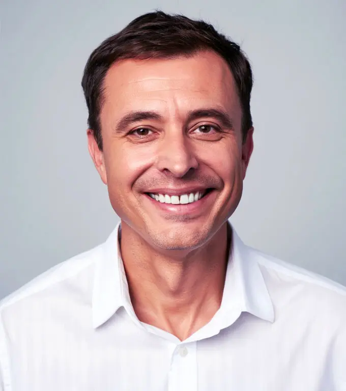 Close-up portrait of a smiling man in a white collared shirt.