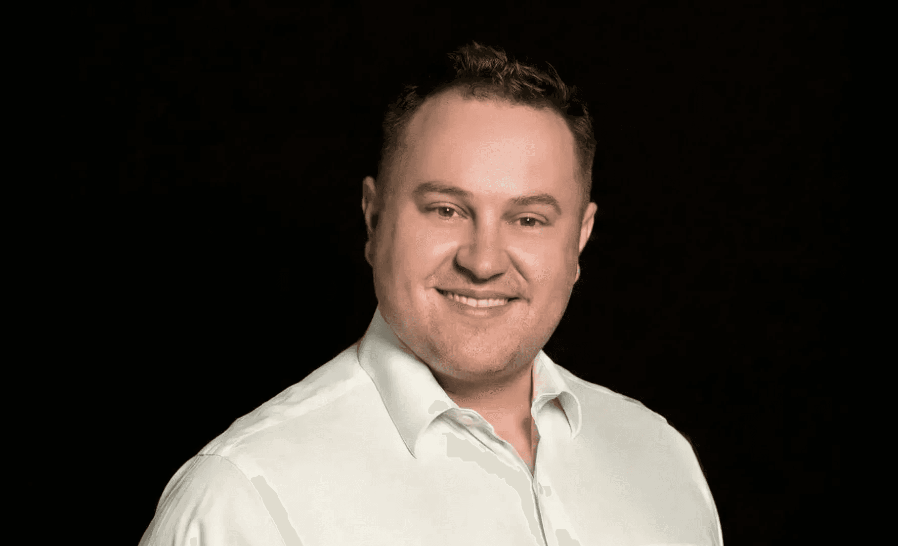 Professional headshot of Adam Lawrence wearing a light colored shirt, smiling at camera