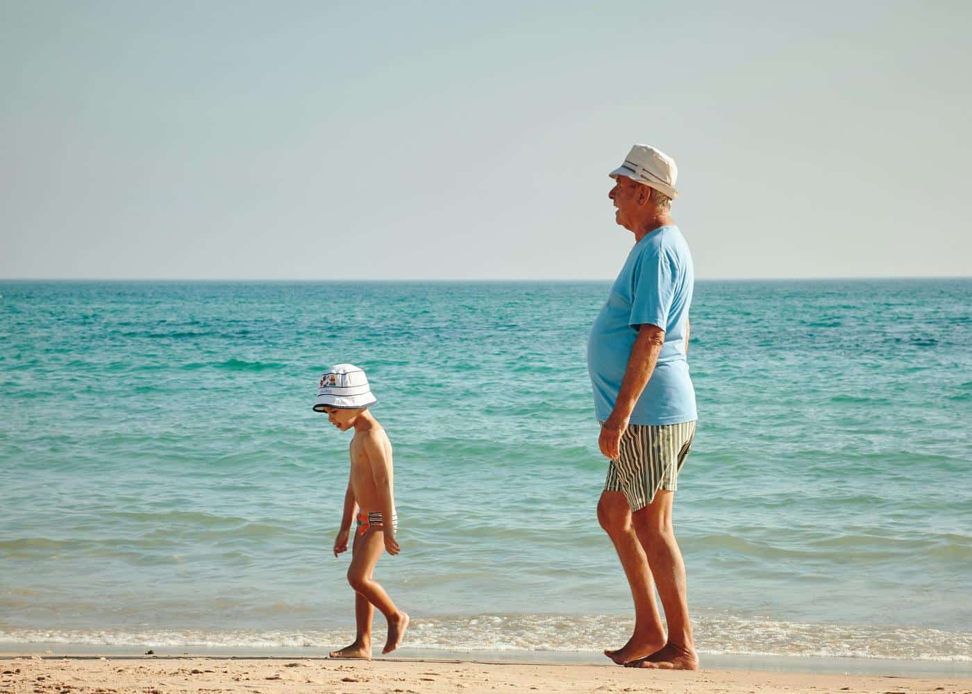 Elderly man and young boy walking on the beach