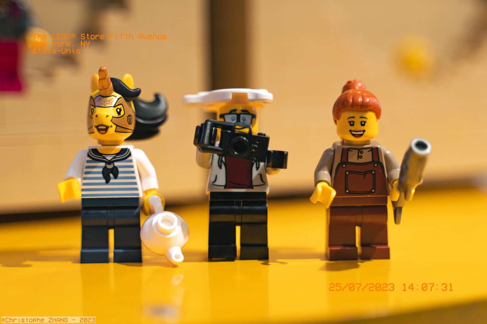 Trois mini-figurines LEGO avec accessoires au LEGO Store, sur fond jaune.