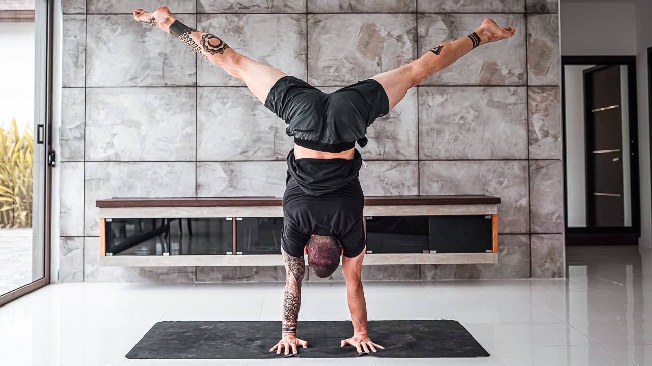 Bre kneeling on a yoga mat, appearing stressed and holding her head. 