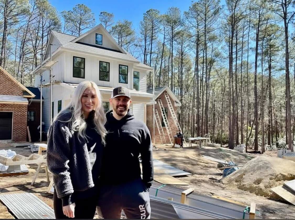 Happy homeowners standing in front of their custom home under construction with South Eastern General Contractors in North Carolina