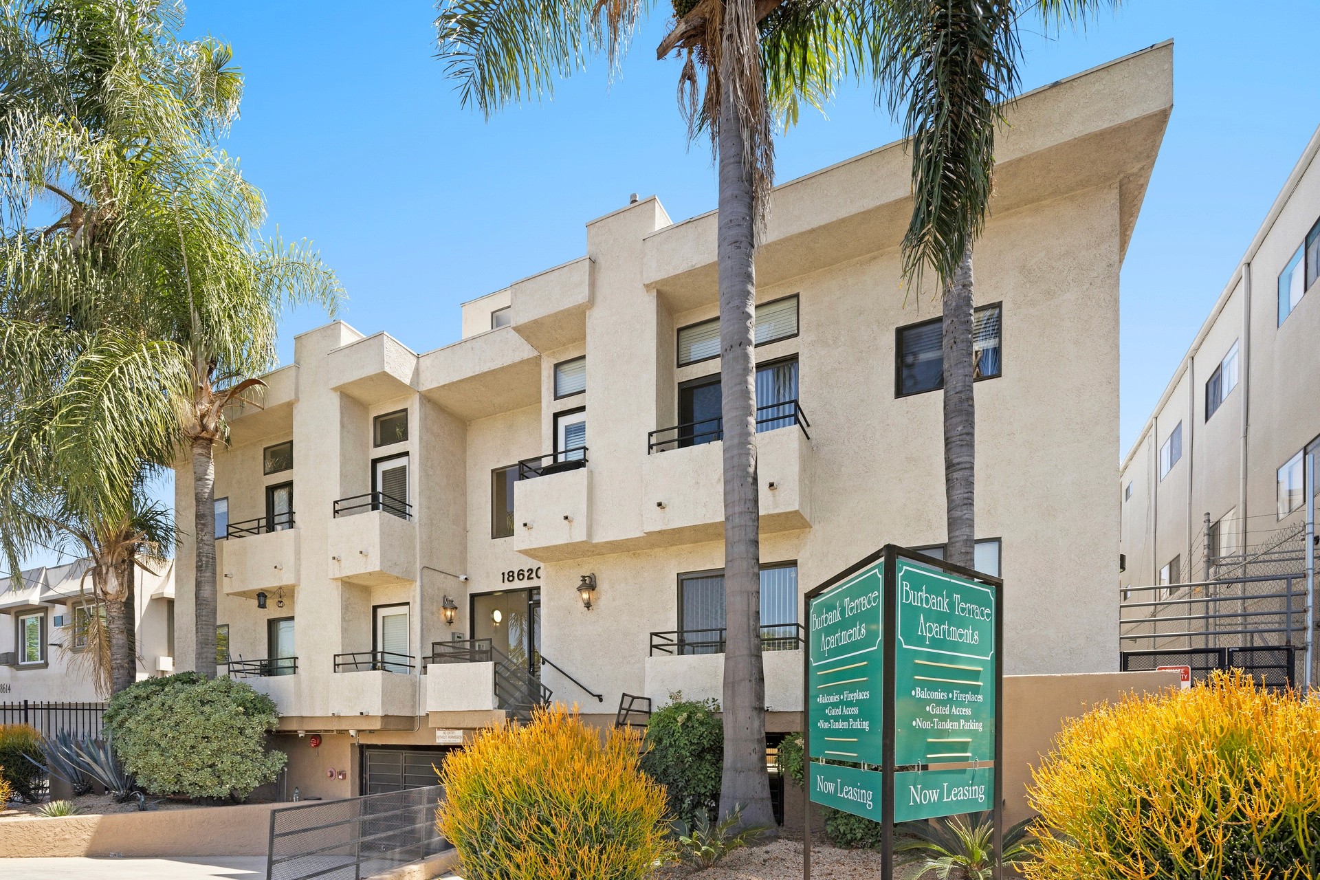 Street-facing view of 18620 burbank blvd with apartment signage and palm trees.