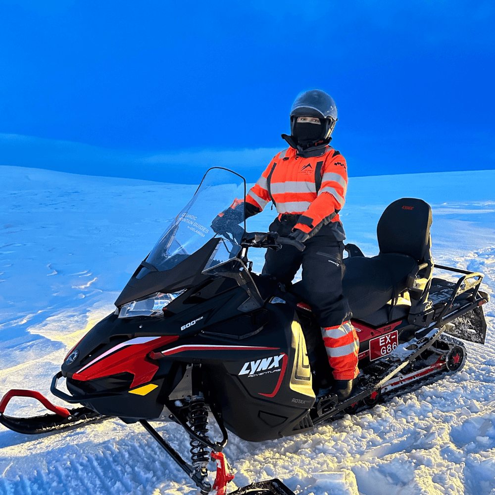 Person riding a snowmobile on Mýrdalsjökull glacier in South Iceland near Vík, a popular glacier adventure activity above Katla volcano.