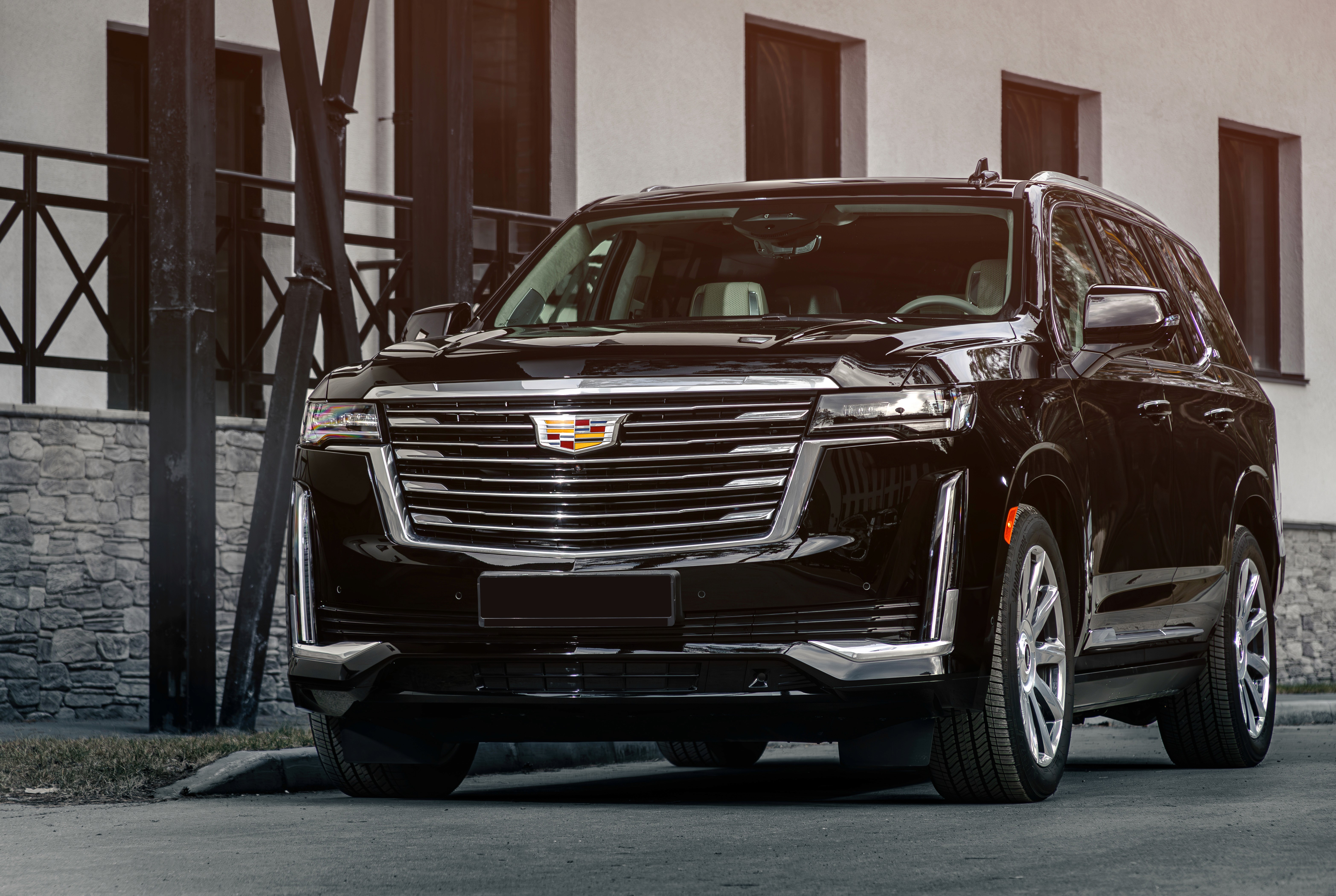 Black Cadillac Escalade SUV parked in front of a modern building, showcasing luxury design and spaciousness, relevant to States Car Service's high-end transportation offerings.