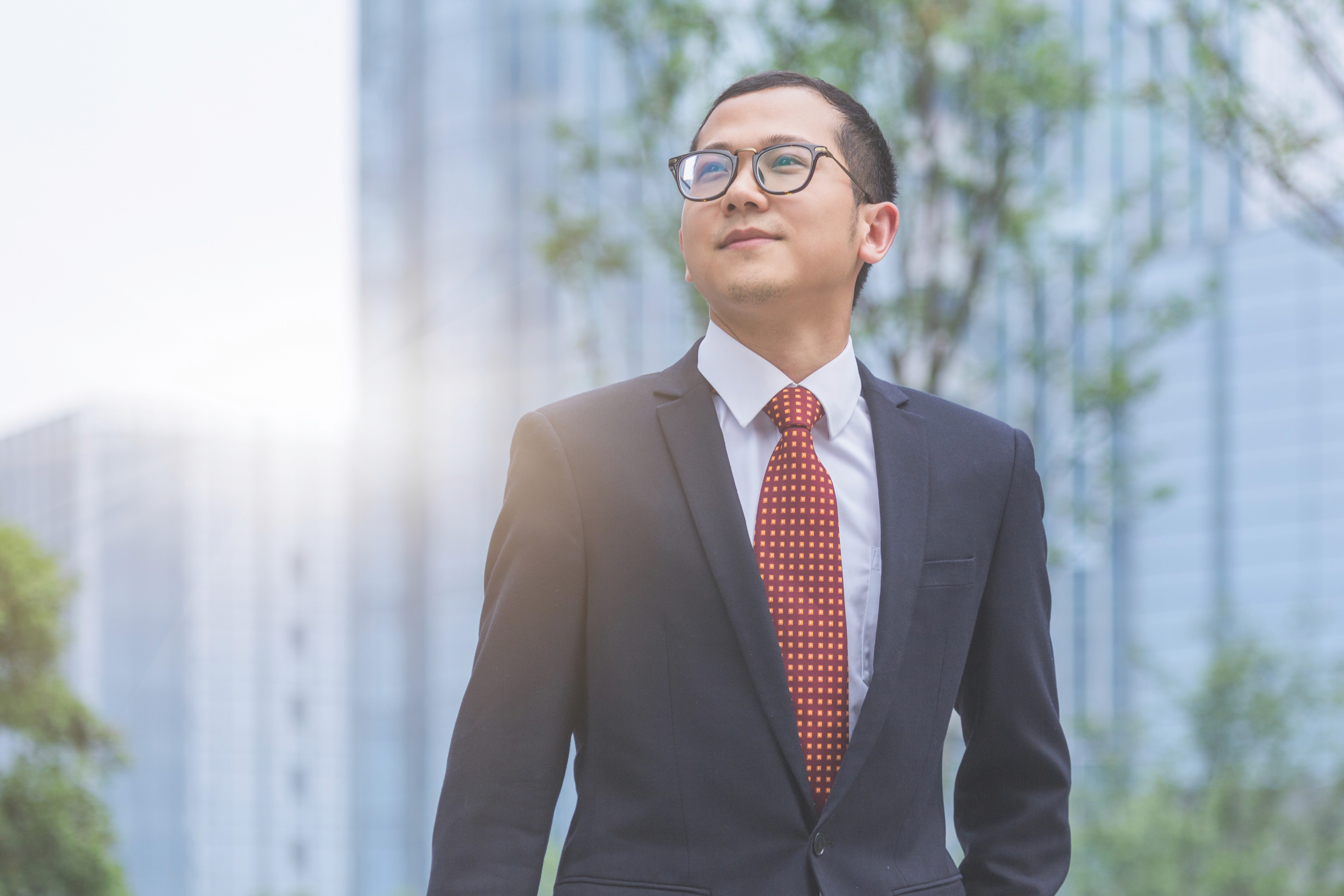Black-and-white portrait of a woman with hair tied back and hoop earrings, wearing a patterned blazer and looking directly at the camera.