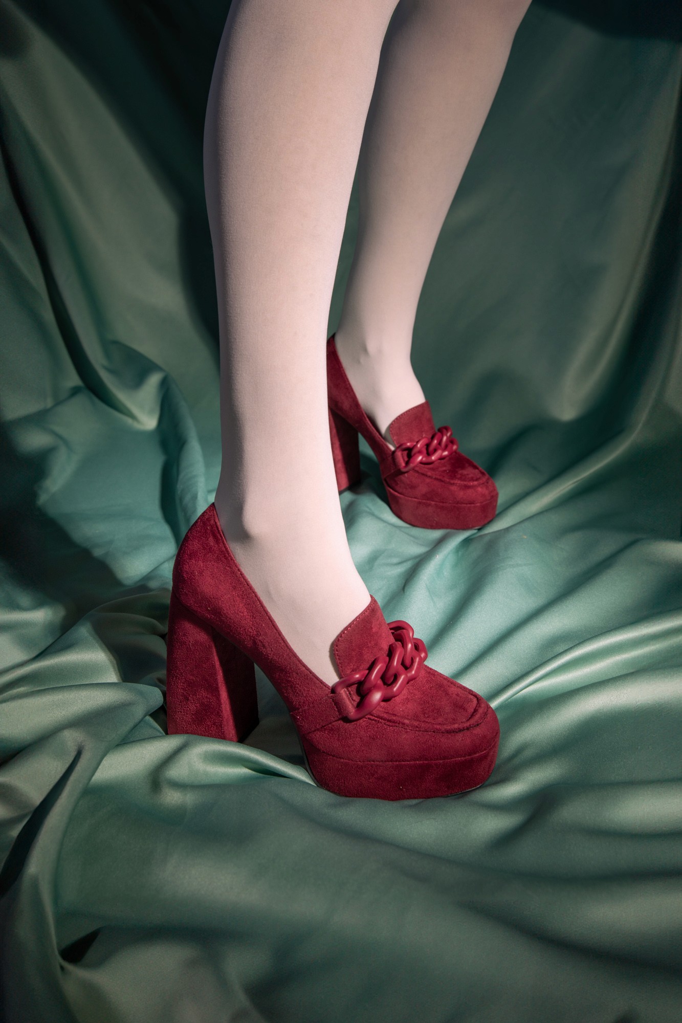 Stylish high-top sneakers featuring a combination of brown, cream, and navy blue leather details, worn with dark rolled-up jeans on a rustic wooden floor.