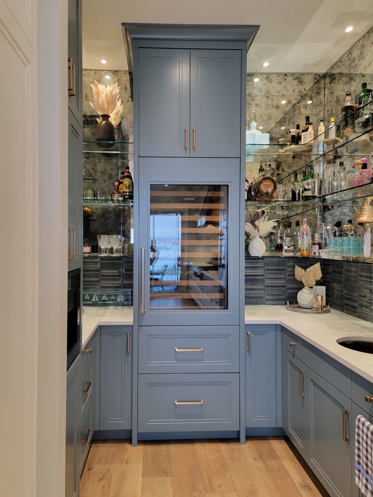 Image of Luxury kitchen interior with blue cabinets, wine fridge, and wet bar featuring KHD Homes design-build renovations.