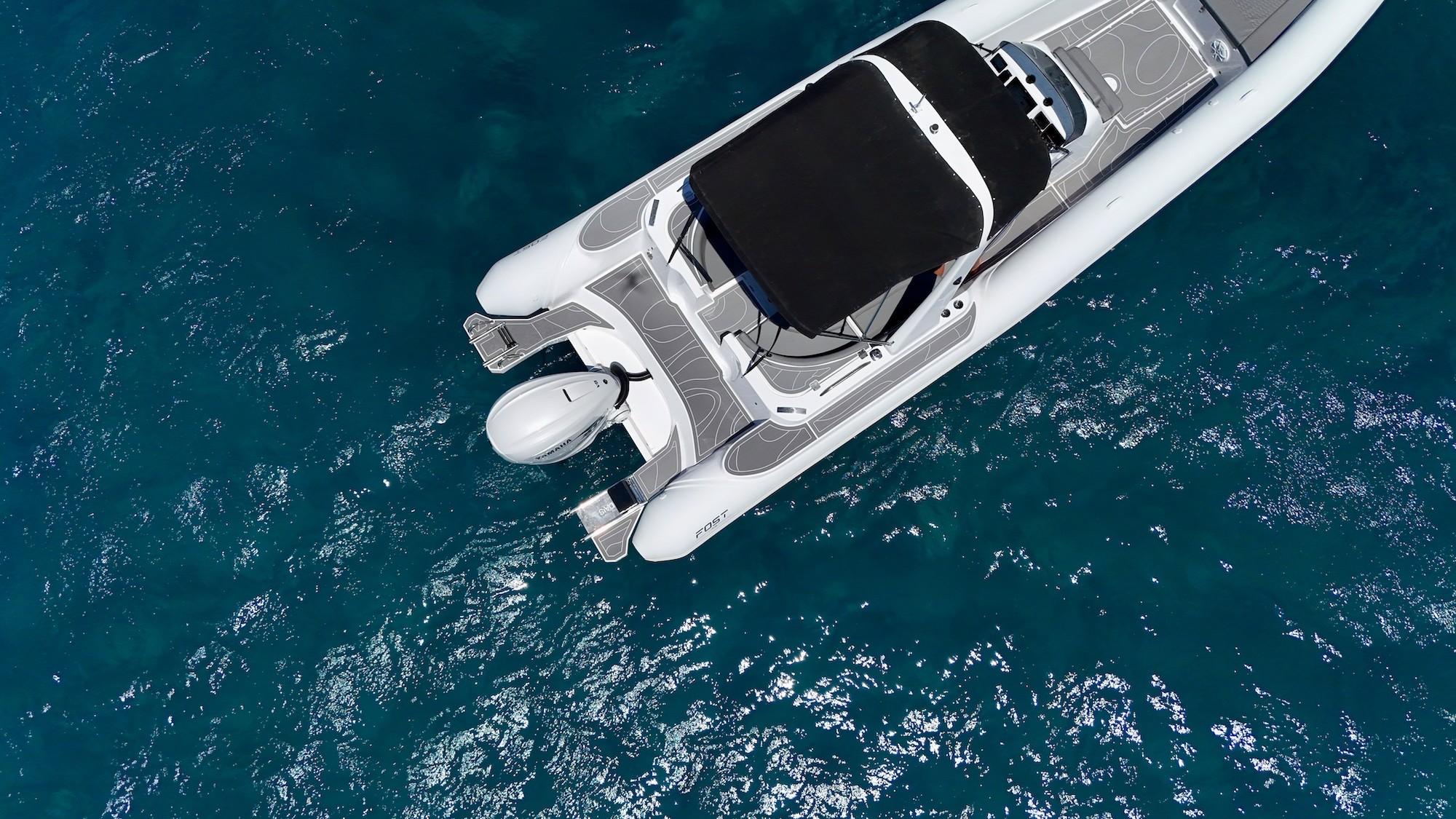 White Fost Matrix 32 speedboat with black T-top canopy cruising on crystal blue Mediterranean waters with passengers aboard.