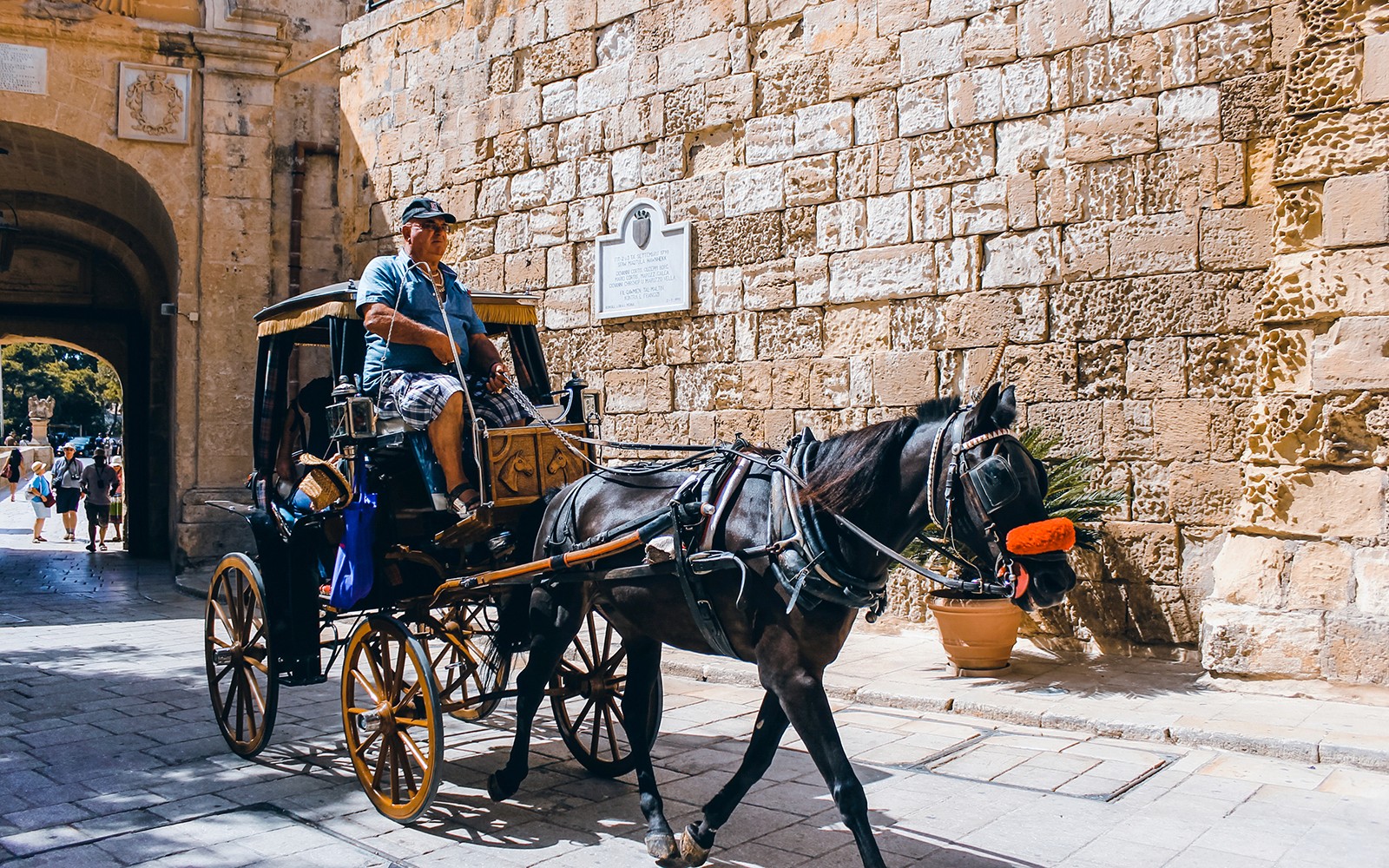 Horse-drawn carriage passing through Mdina's historic stone gate.