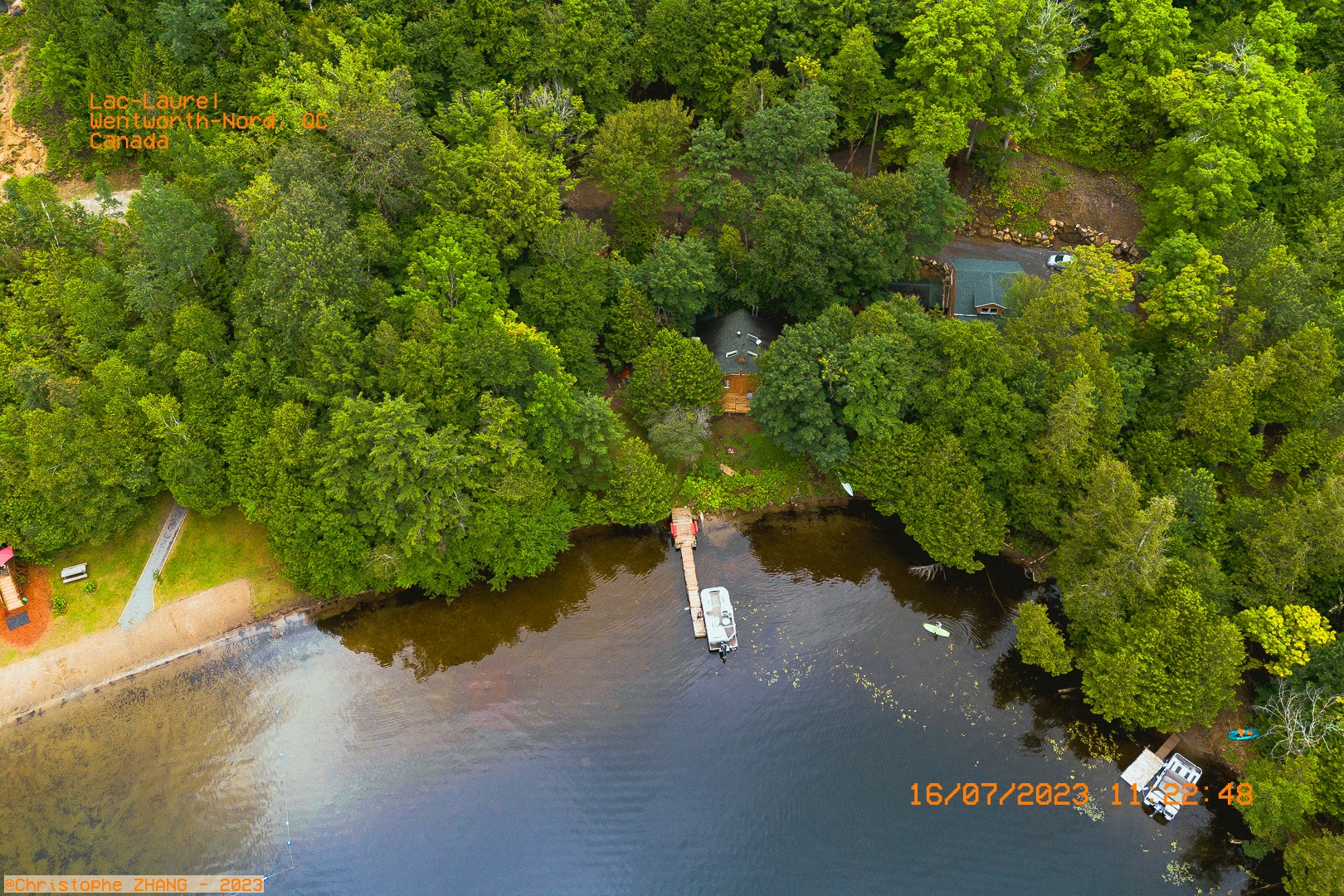 Chalet caché dans les arbres avec un quai menant au lac Laurel, capturé en drone.