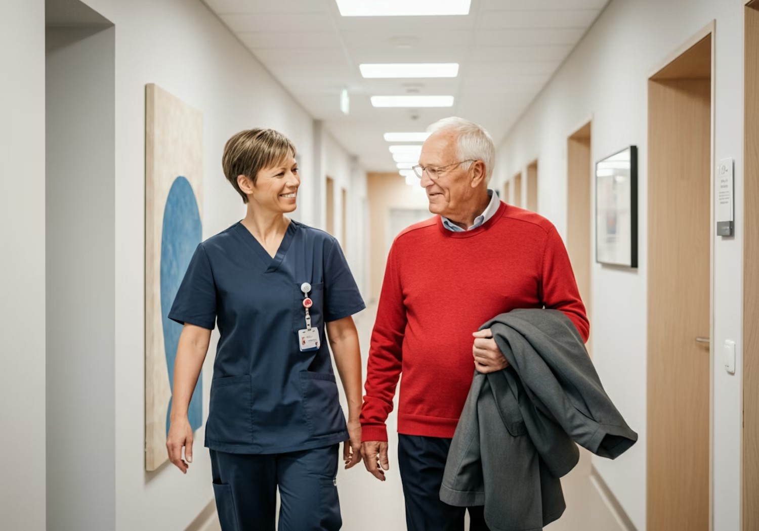 Nurse assisting elderly patient in hospital hallway