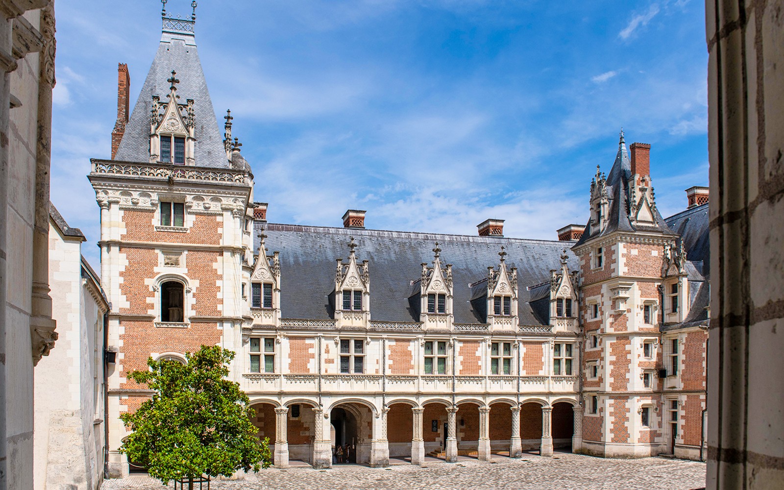 Royal Blois Castle courtyard with ornate architecture and blue sky.