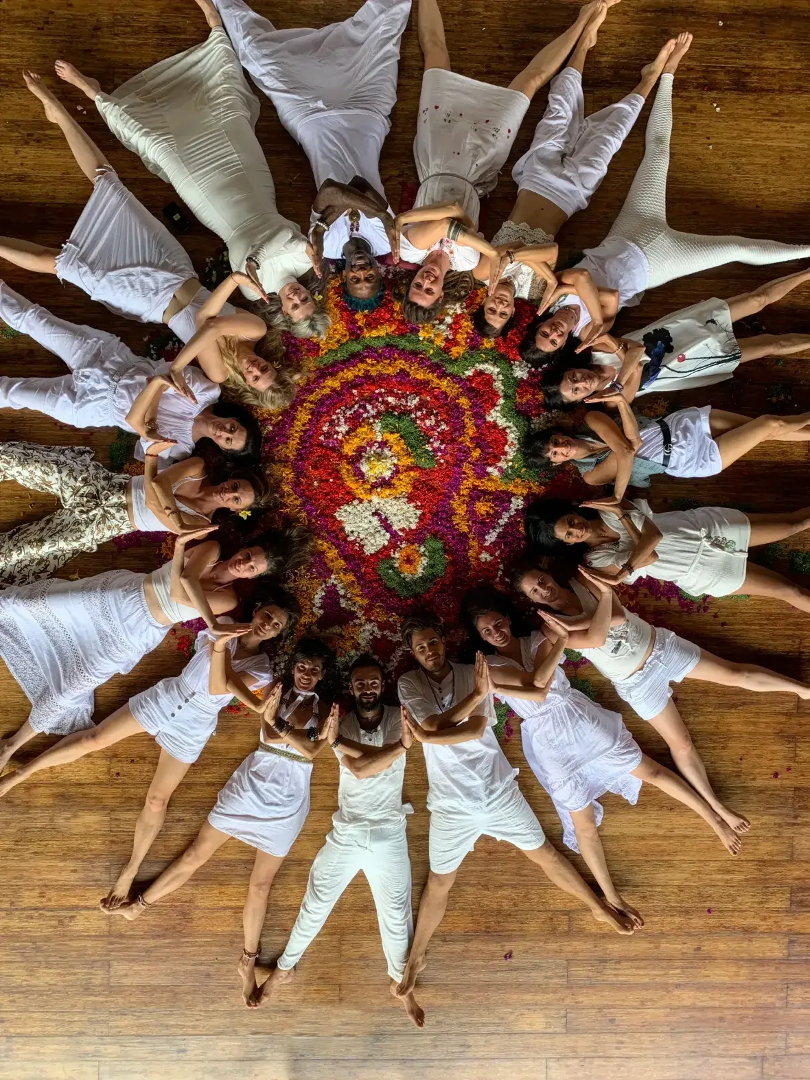 Ulu Yoga teacher training community dressed in white gathering around a traditional Balinese flower mandala for graduation