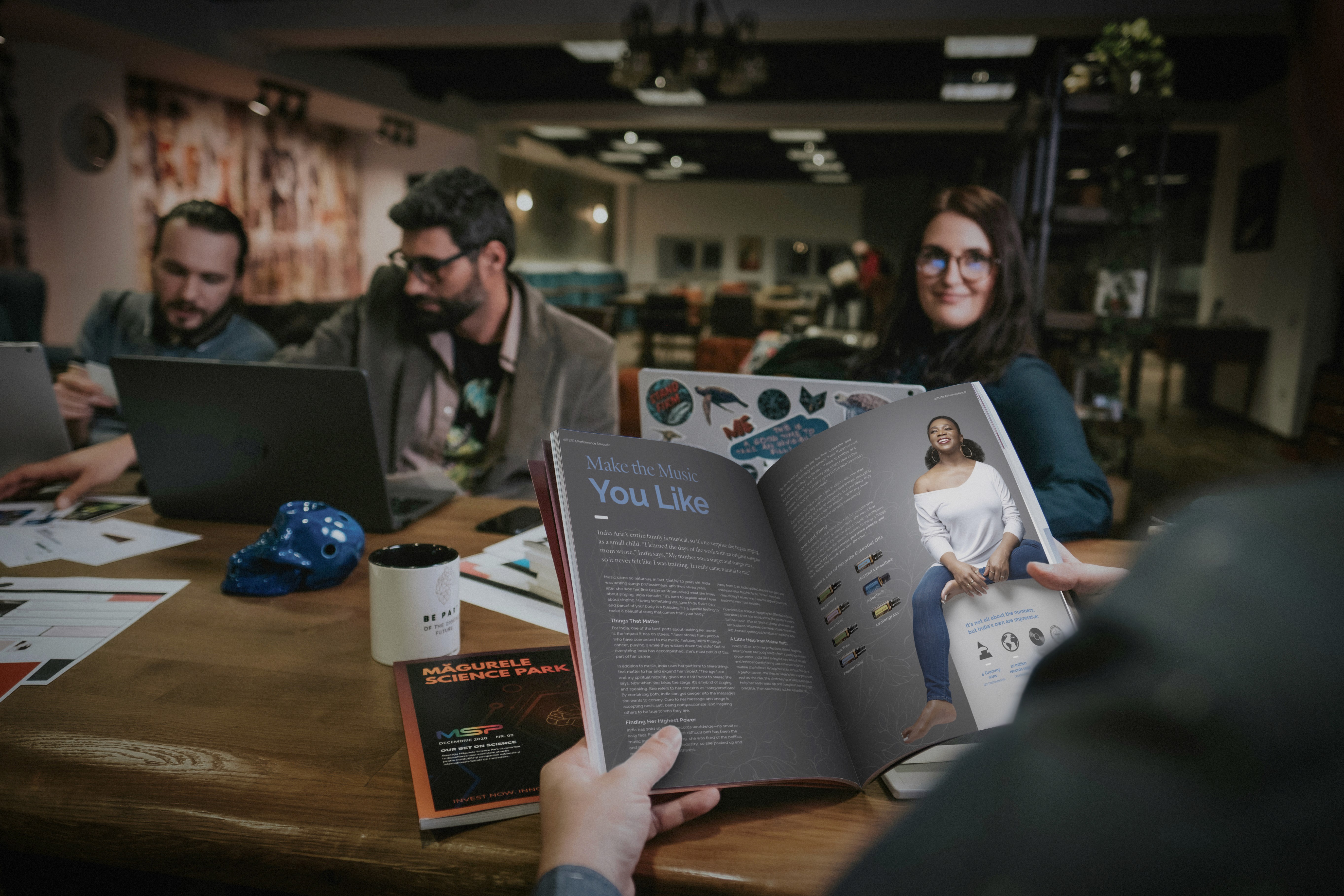 Team working around a table while reviewing a printed magazine spread in a studio setting.