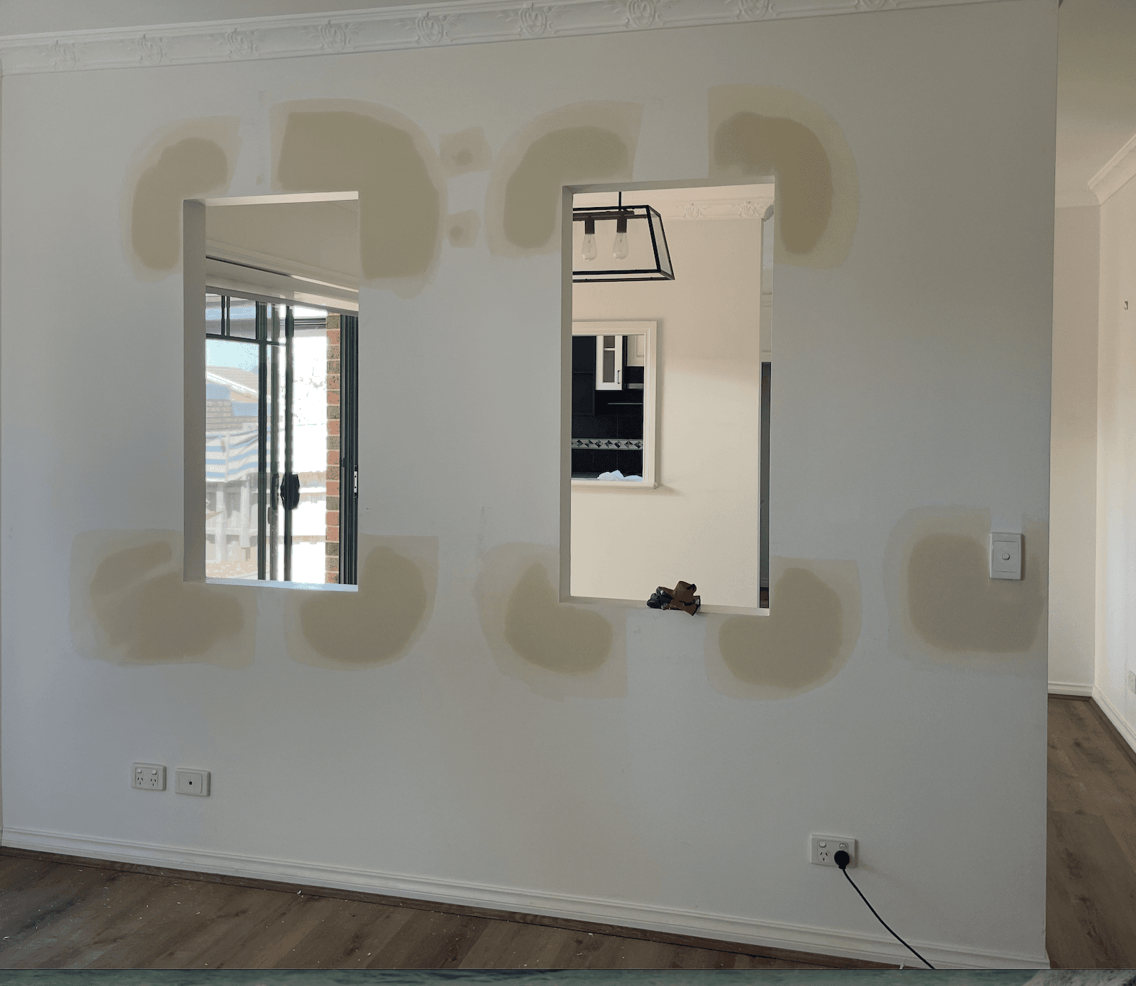Modern kitchen with a wooden dining table, white chairs, and a hanging light fixture above.
