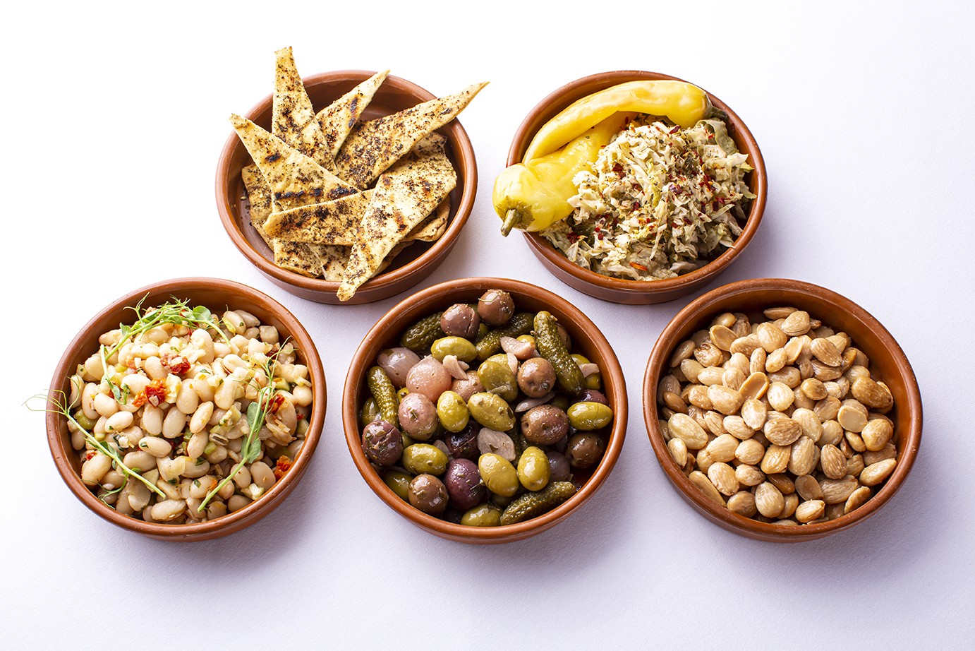 Five clay bowls of tapas with olives, almonds, flatbread and salads at Barcelona Restaurant