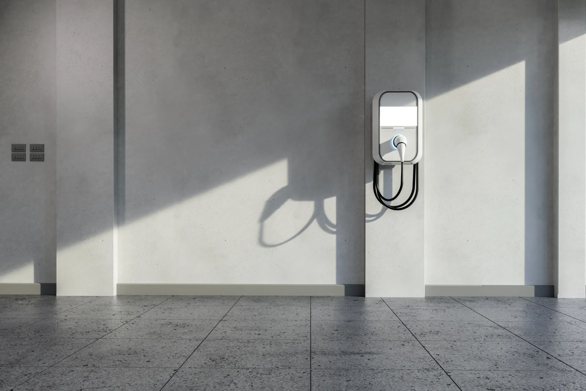 Eine Wallbox auf einer weißen Hauswand mit einem schwarzen Stecker für das Auto.