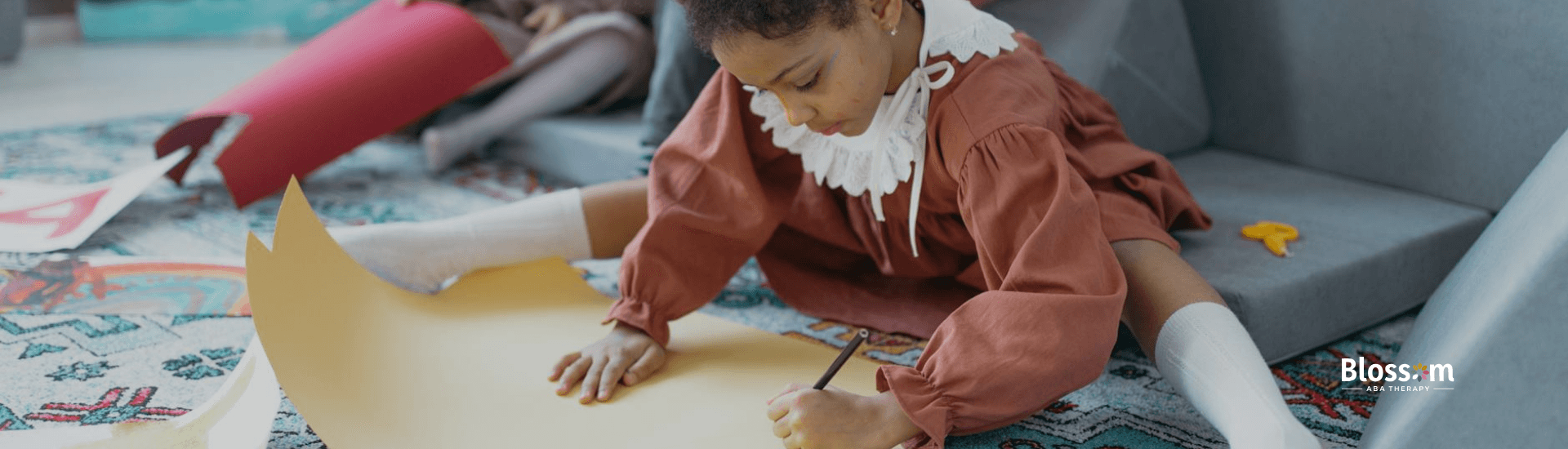 Autistic girl in a dress sitting on the floor, focused on drawing on a sheet of paper in Virginia.