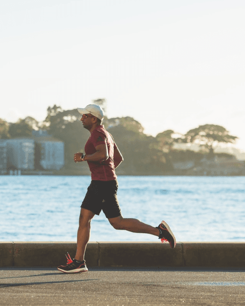 person running in working clothes in front of water