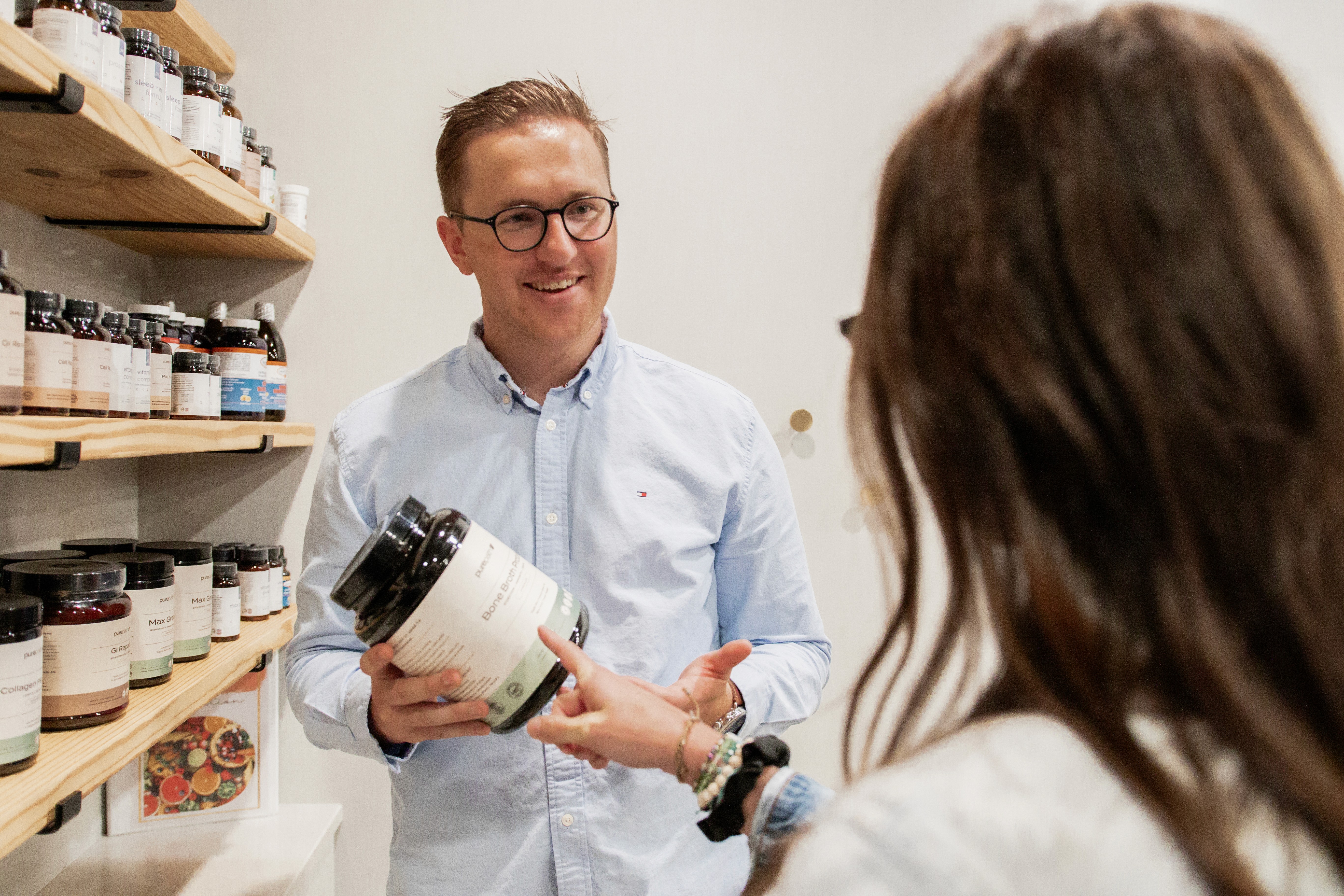 Two Premier doctors sitting on a couch in the office, smiling at each other in conversation.