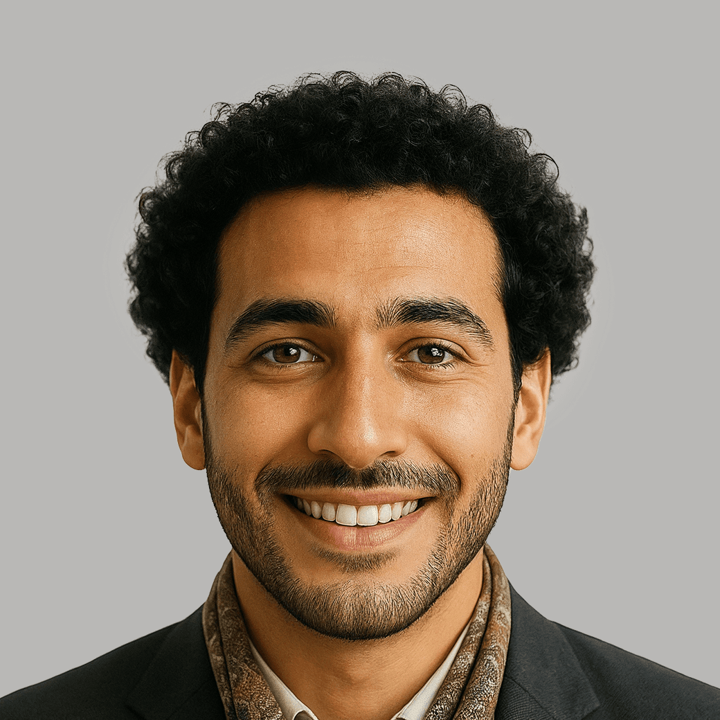 Smiling man with curly dark hair, beard, and patterned scarf.