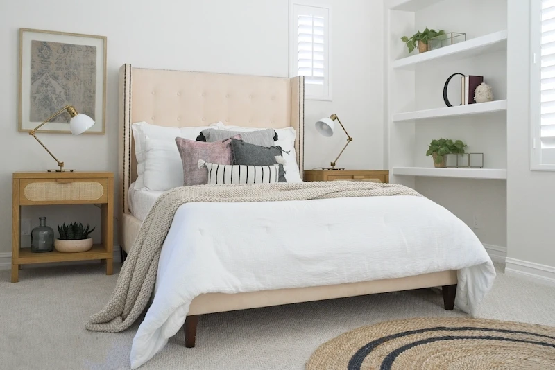 Serene bedroom with natural wood headboard, white linens, and built-in shelving in Bonita Canyon Remodel.