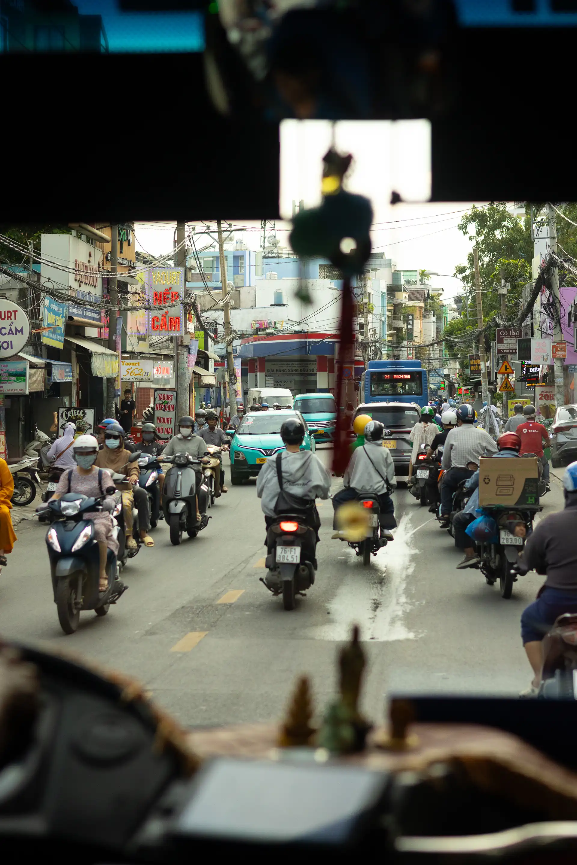 A crowded street in Ho-Chi-Minh full of scooters and shot from within a bus