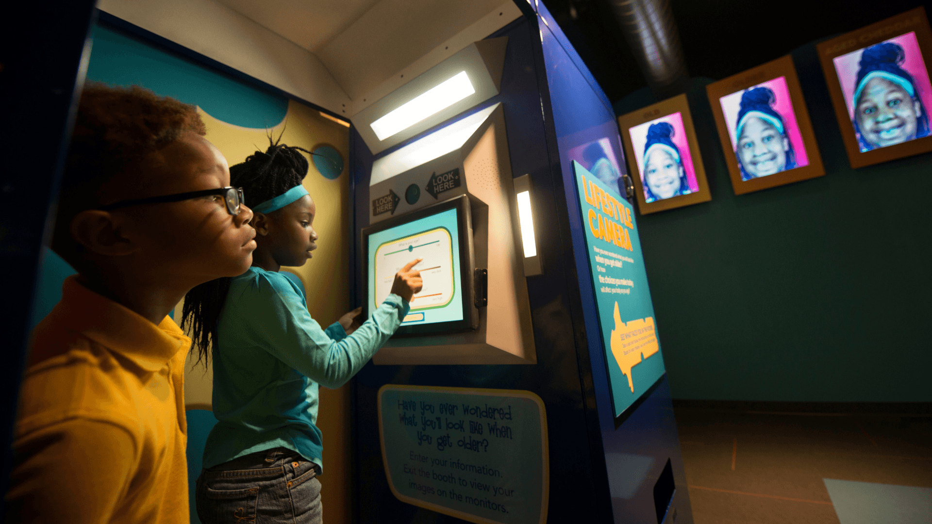 A girl takes a picture of herself to see what she will look like in the future as a young boy watches.