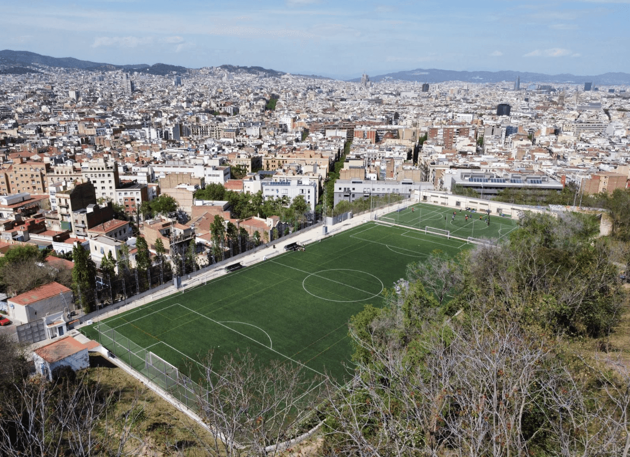 Satalia Municipal Soccer Field in Barcelona, met op de achtergrond de stad en een helderblauwe lucht.