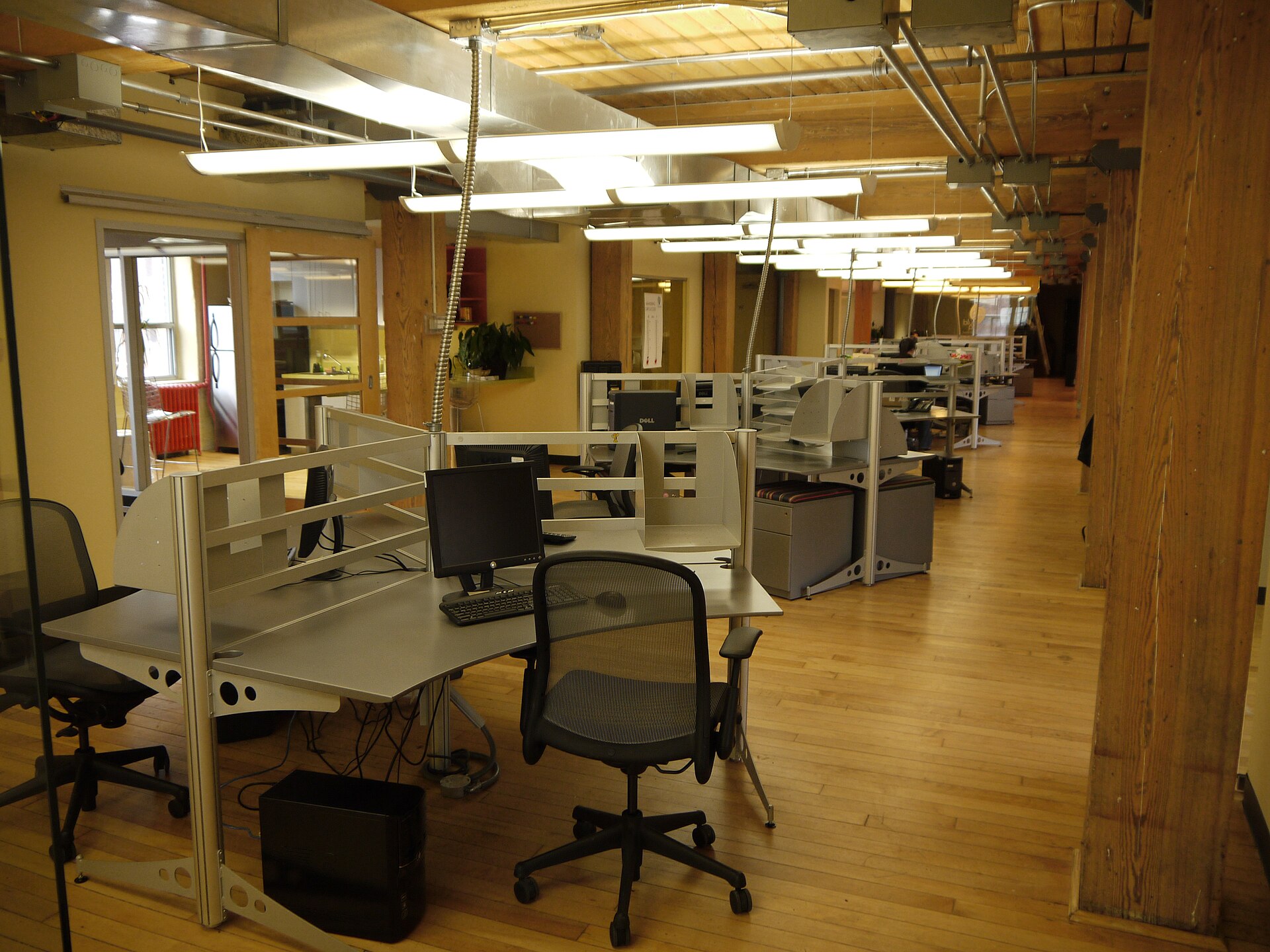 An open-plan office floor with rows of desks, monitors and low dividers.