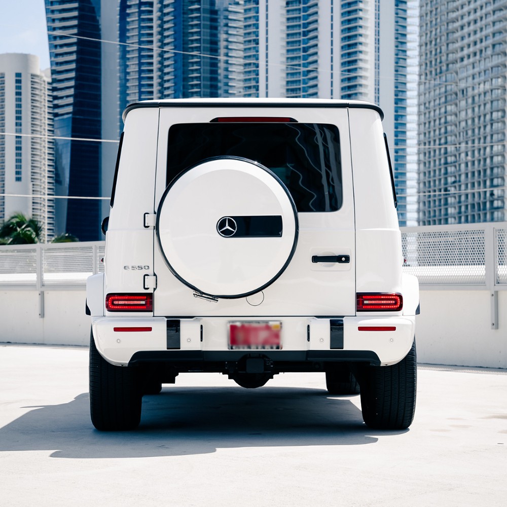 Rear view of a white Mercedes-Benz G 550, highlighting its rear-mounted spare tire and classic G-Wagon styling.
