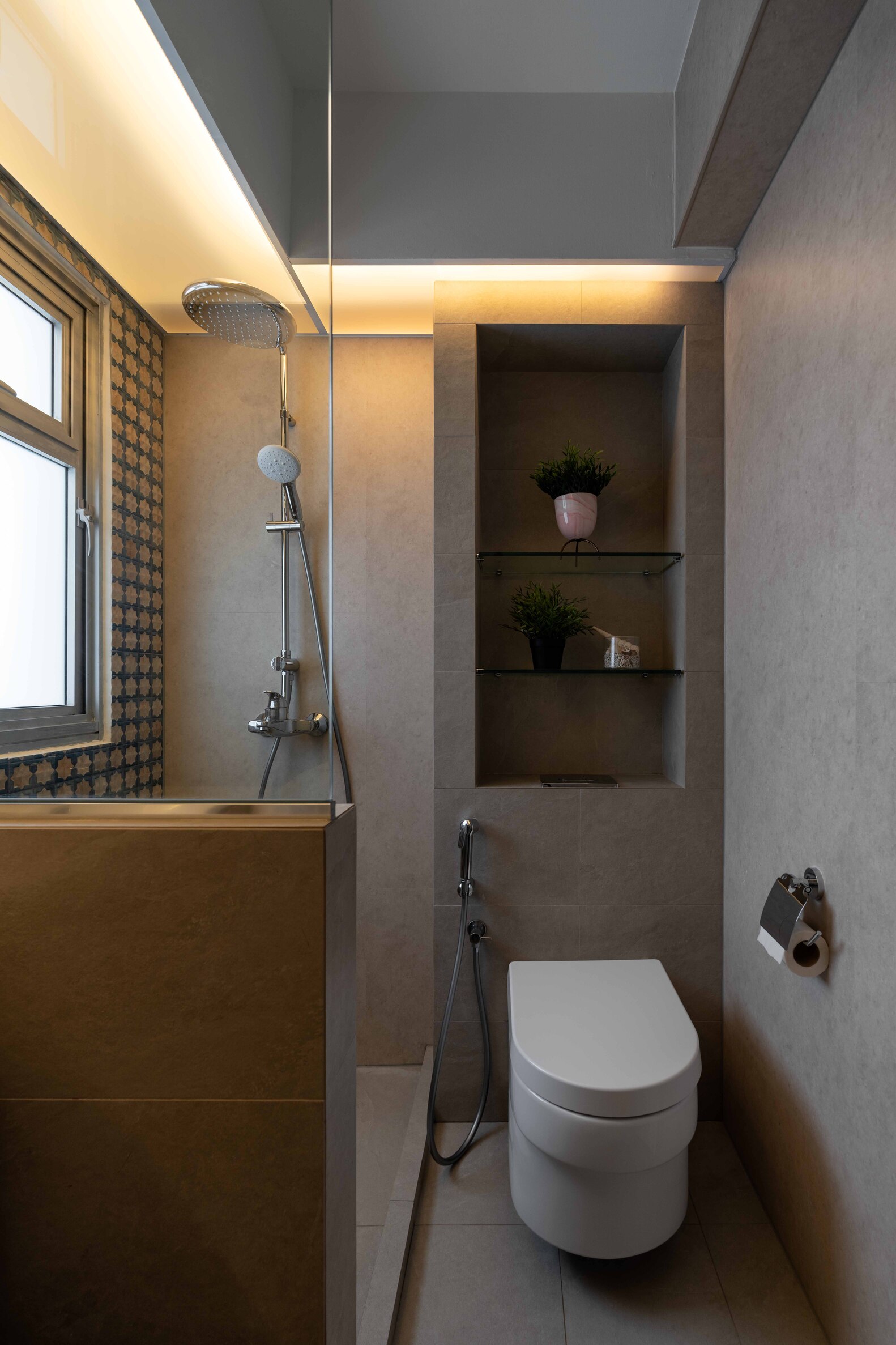 A modern bathroom featuring a toilet, shower, and minimalist design with natural lighting.