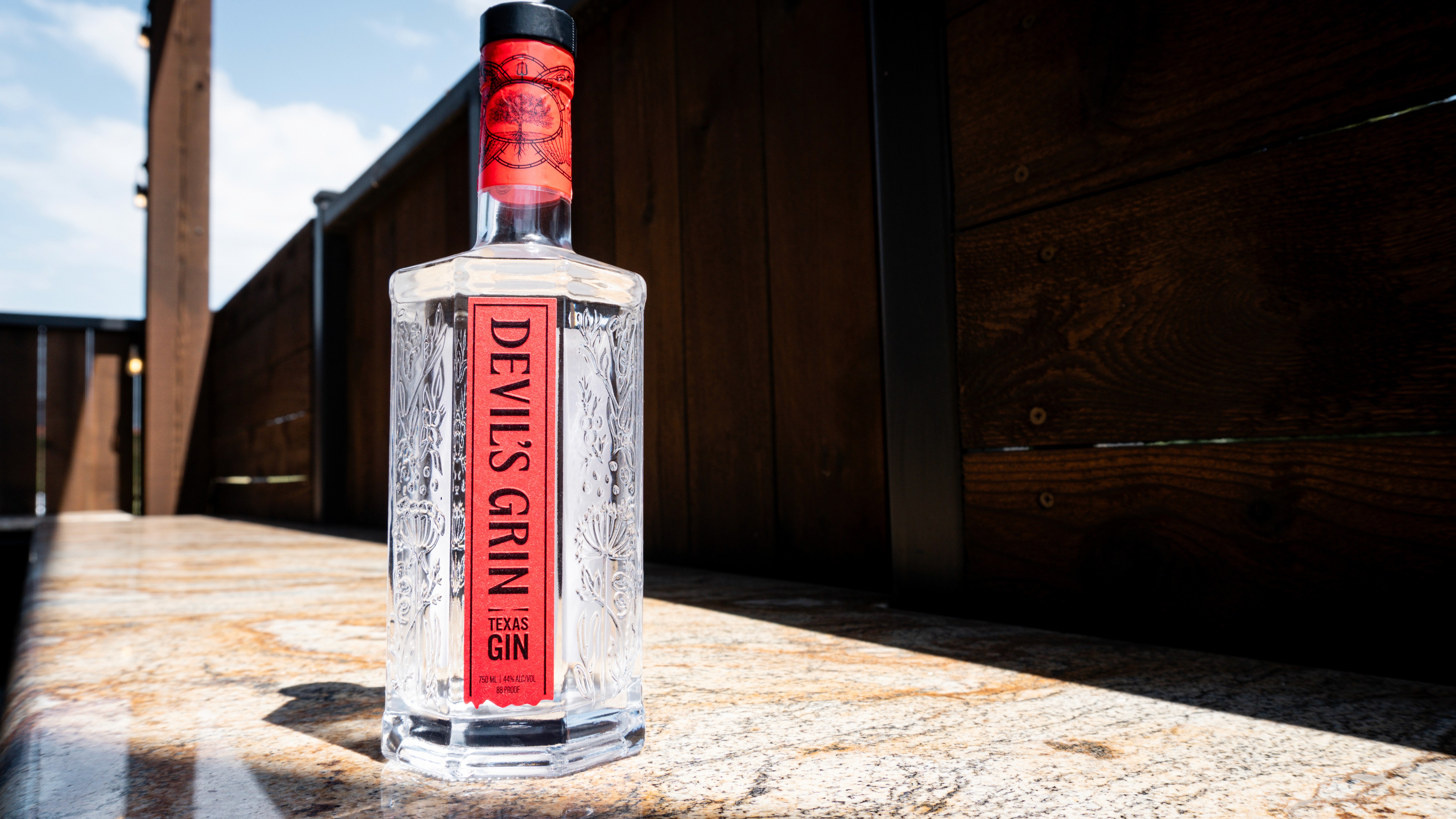 Devil’s Grin Gin bottle photographed in natural light against dark wood.