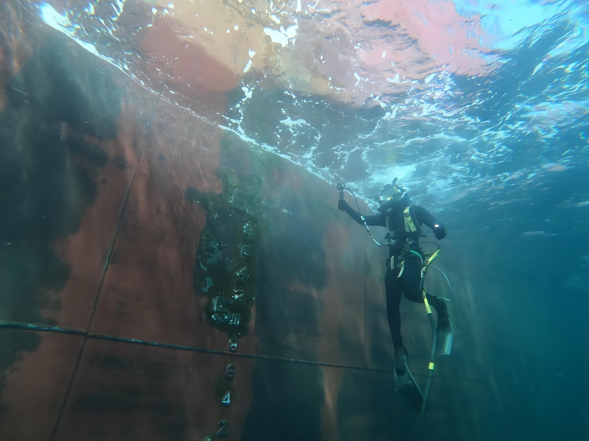Commercial diver conducting an in-water hull inspection along a vessel’s shell plating—evidence-led condition assessment and biofouling compliance support.