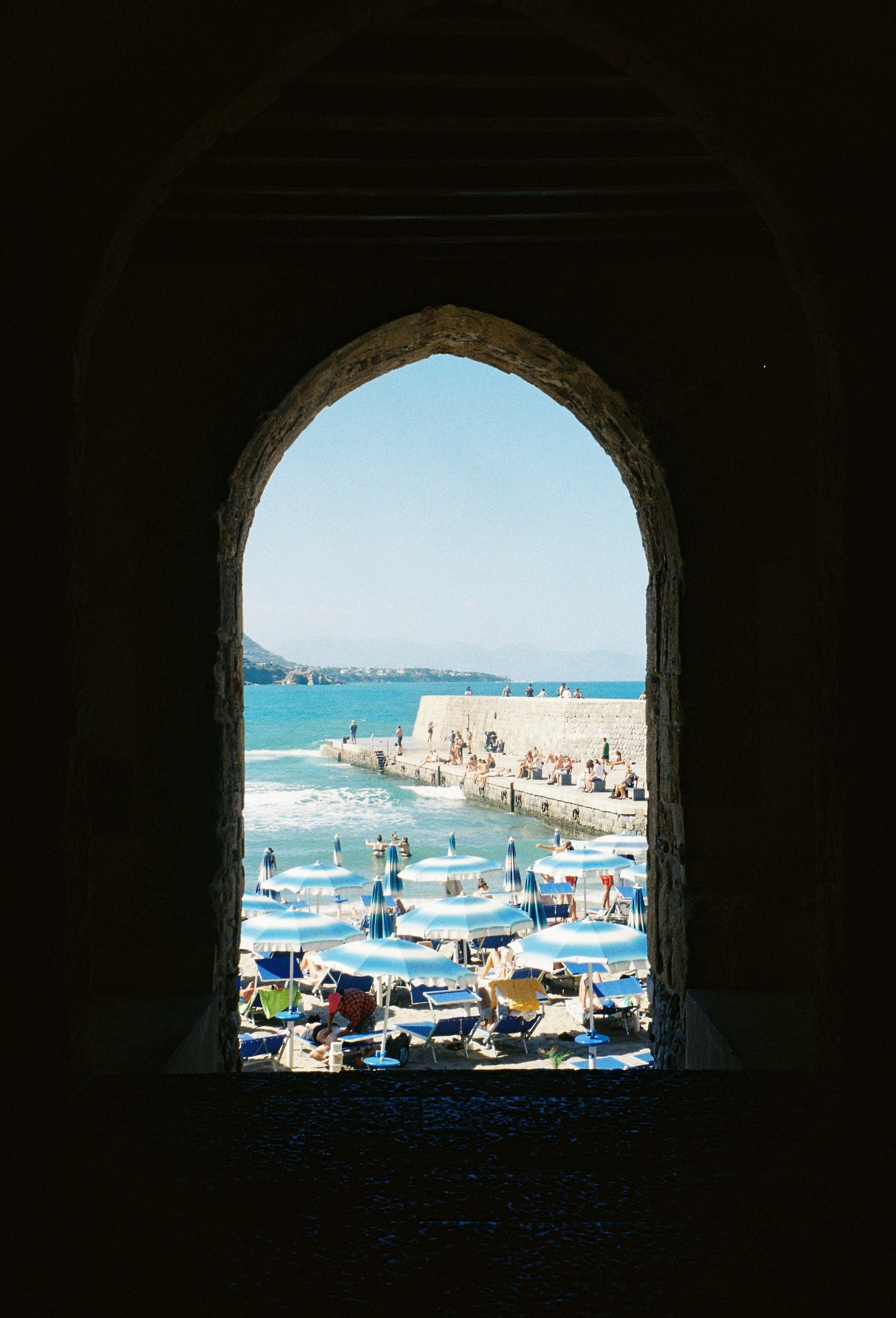 Vue panoramique sur une plage via une ouverture architecturale : composition visuelle pour une interface web narrative et originale.